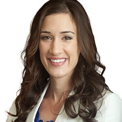 Aenslee Tanner PCC headshot phot, smiling woman with brown hair wearing white blazer and blue top in front of white background
