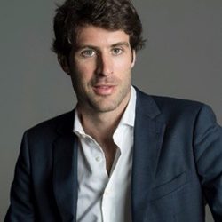 Alvaro Salvat headshot photo, smiling dark haired man in a dark blazer against a gray background