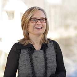 Analia Yacot PCC headshot photo, smiling woman wearing dark clothing and glasses outside