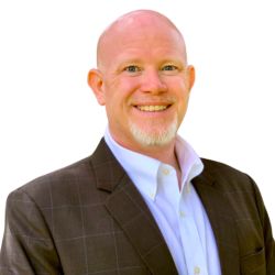 Daniel Aytes PCC headshot photo, blad man with white beard wearing brown blazer and white collared shirt smiling against a white background