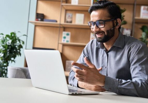 coach smiling with a headset on and speaking to a computer screen on a video call