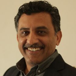 Umer Bhutta PCC SHRM SCP MCIPD headshot photo, dark haired man with dark clothing smiling