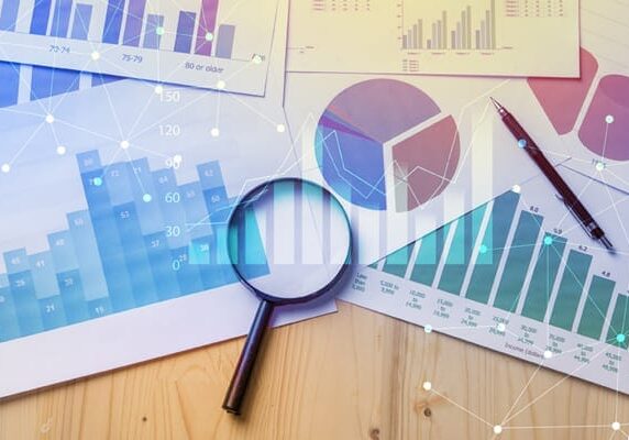 magnifying glass on top of various papers with different graphs on them