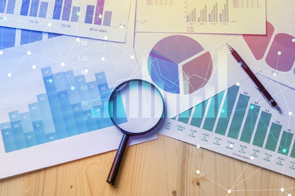 magnifying glass on top of various papers with different graphs on them