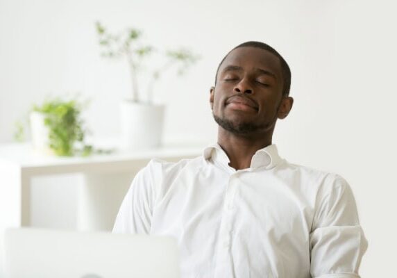 coach sitting back with eyes closed to take a moment for self care