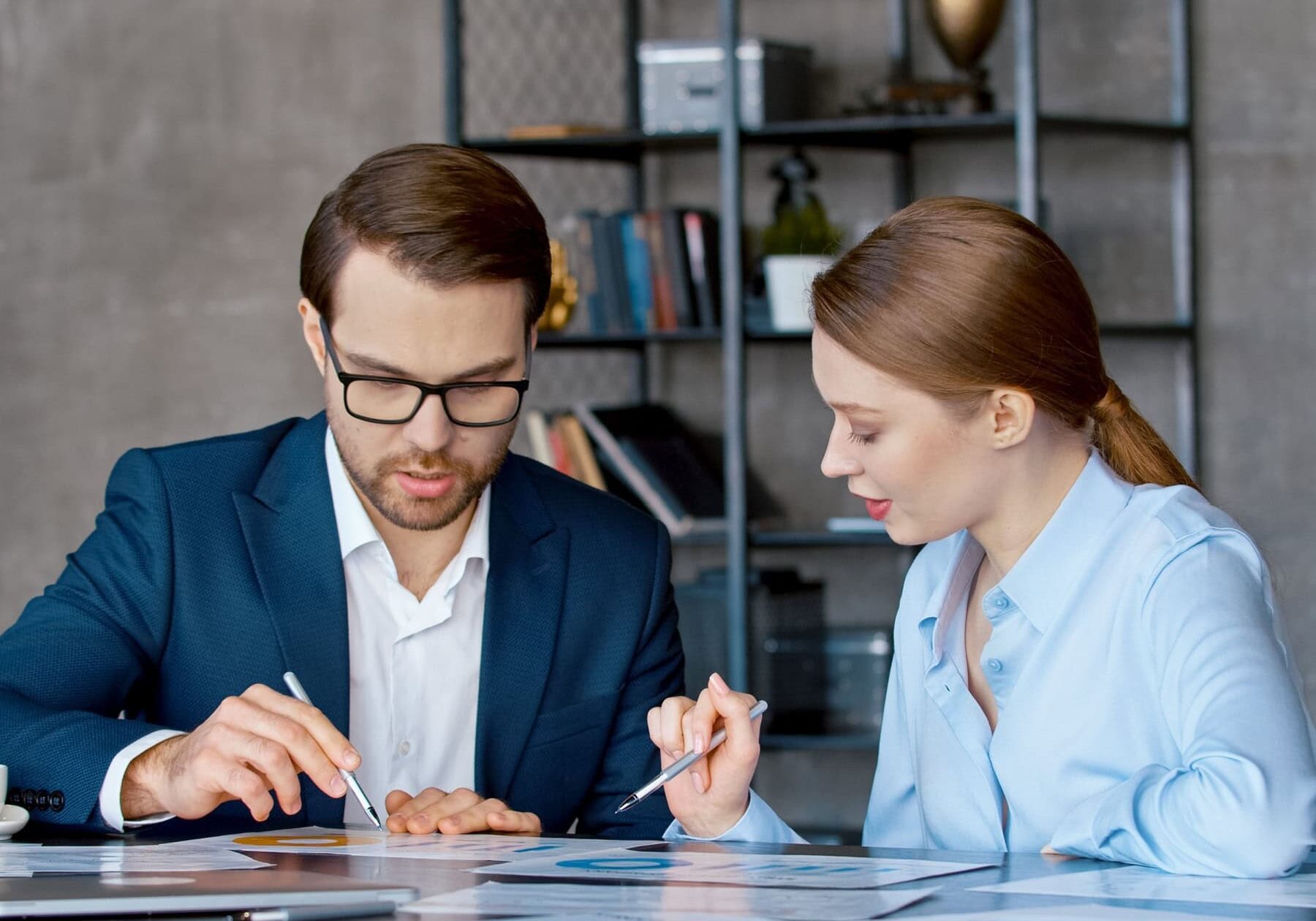 A man and a woman go over the various coaching impact at a table in an office.