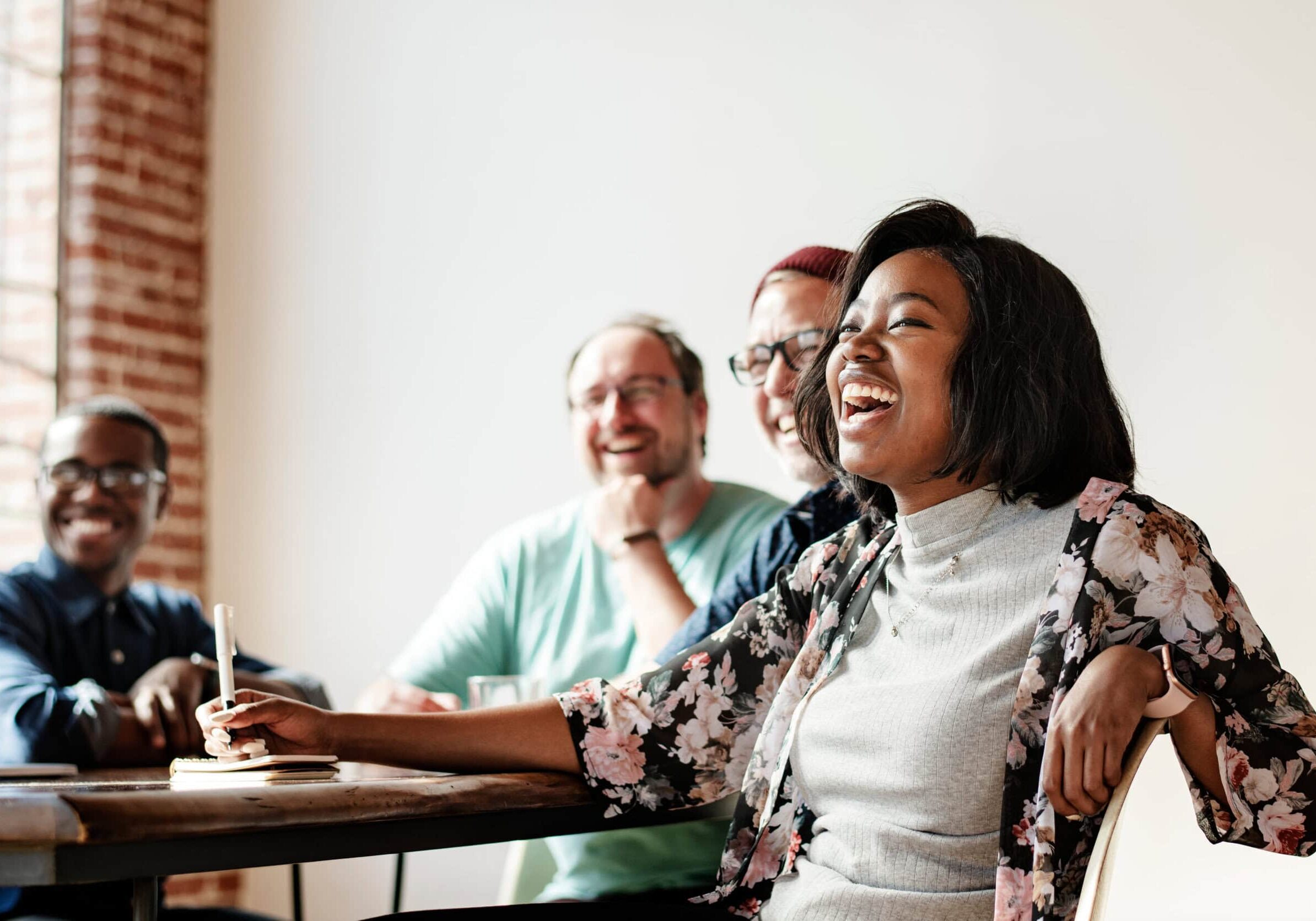 A diverse group of people sharing a joyful moment around a conference table, captures a positive and collaborative coach team meeting, emphasizing an atmosphere of connection.