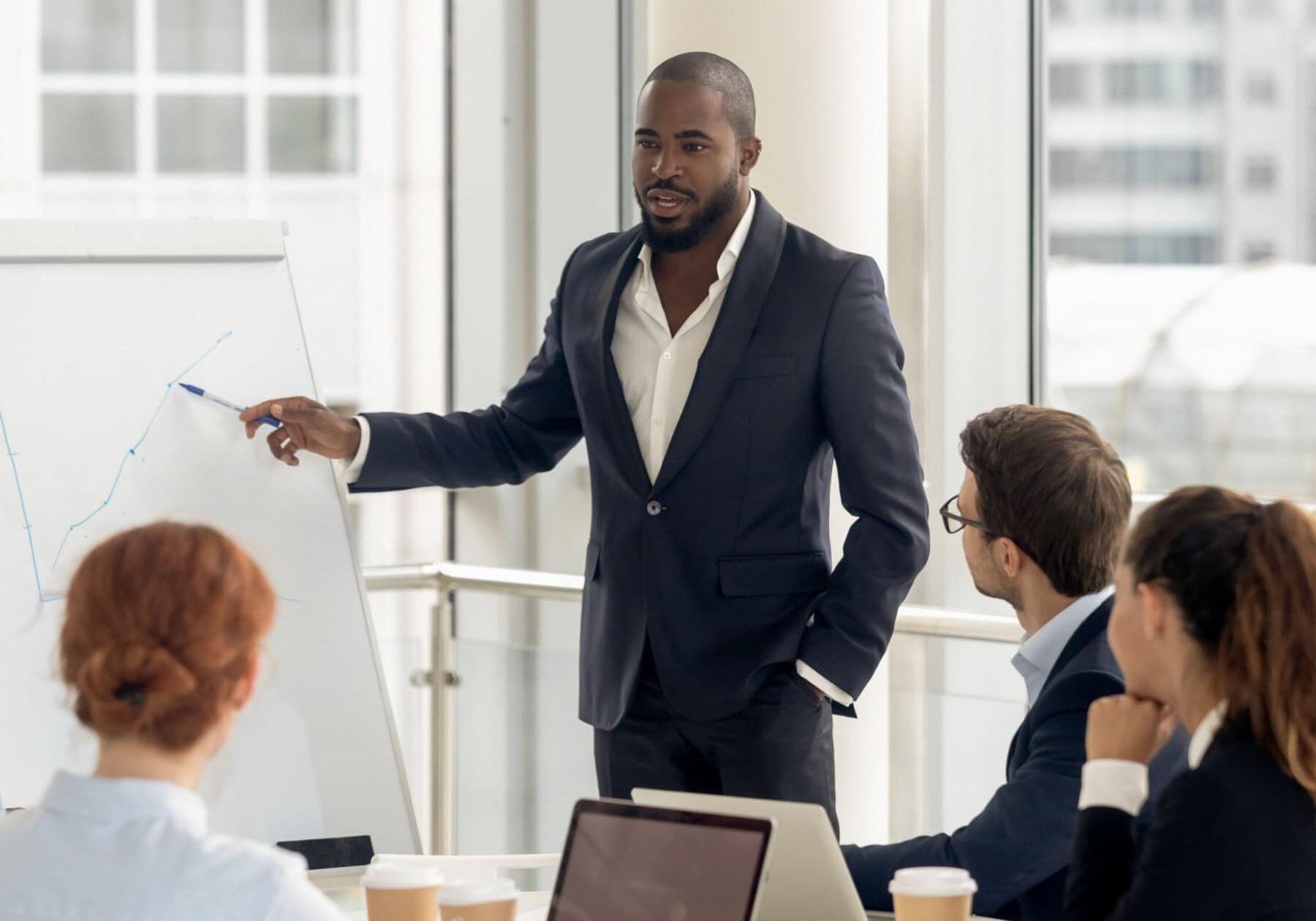 A man explains the ethical complaint process to a group of people in an office.