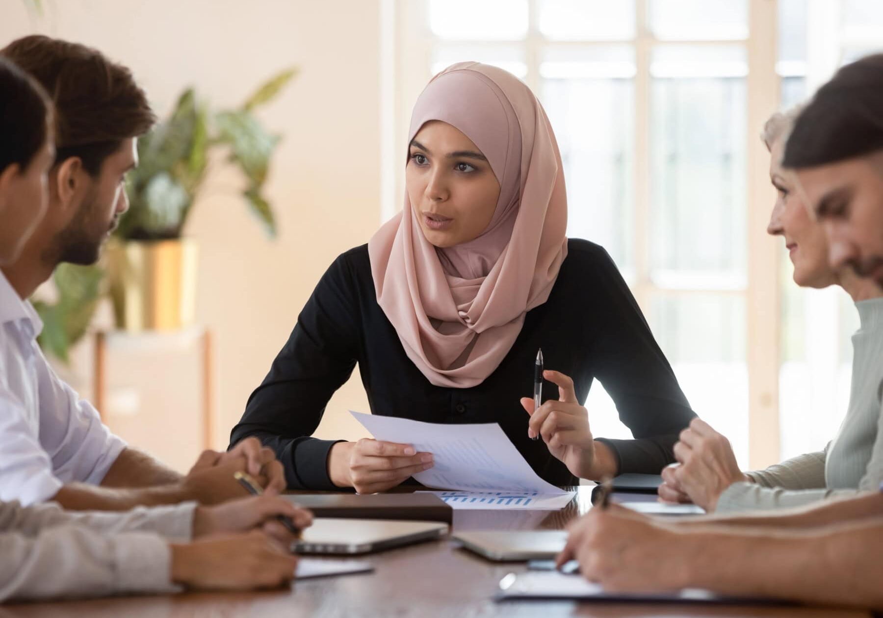 A group learns about the ICF Exam scheduling options sitting at a table.
