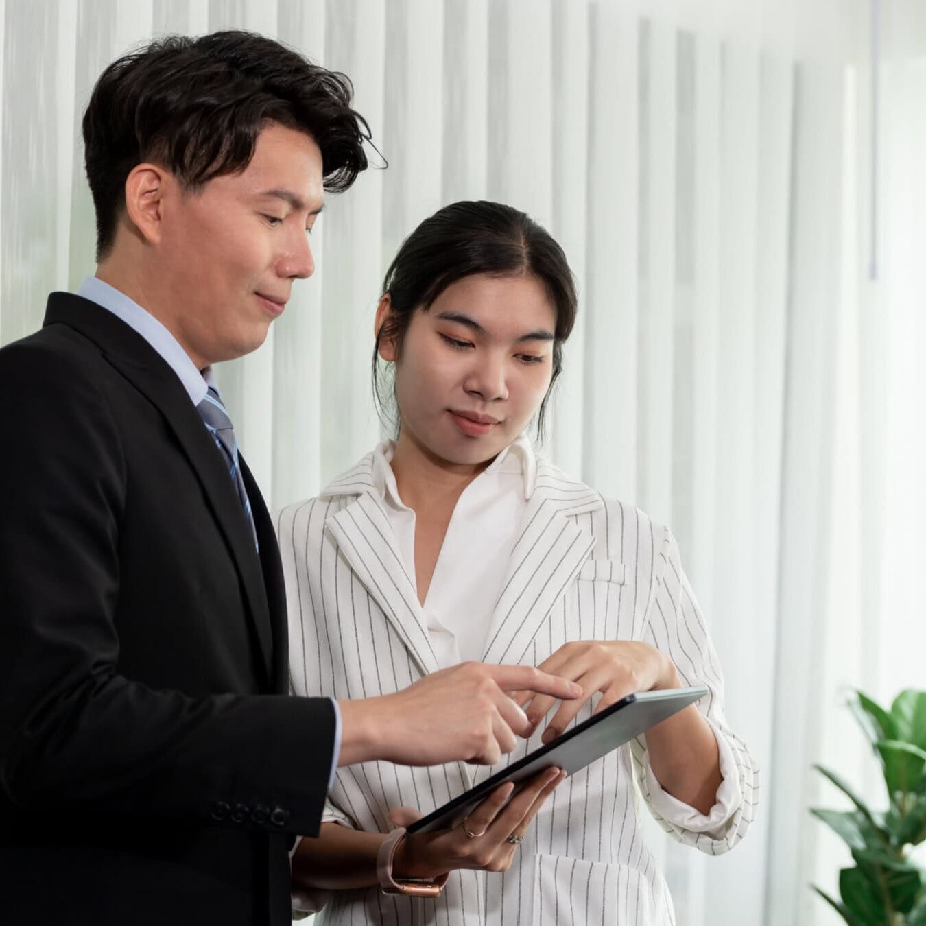 A man and woman work on an iPad in an office setting
