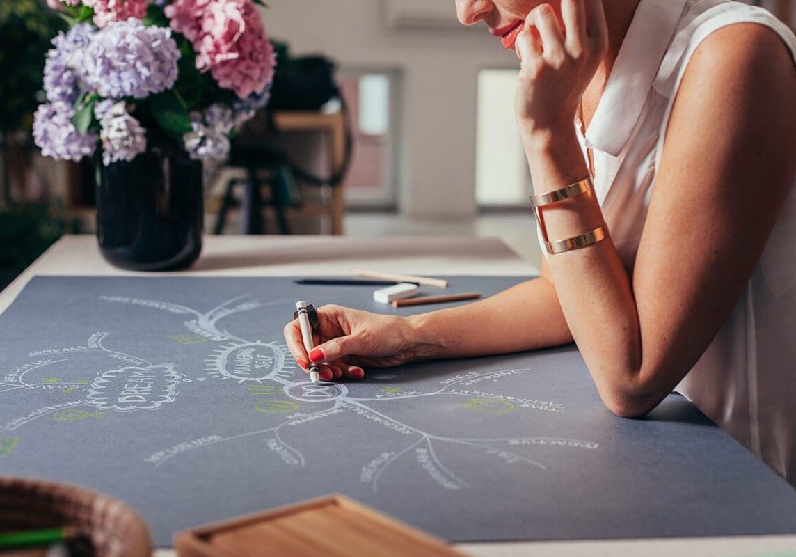 A student coach mapping out a strategic plan or process on a large chalkboard, exemplifying the analytical and creative aspects of coaching education.