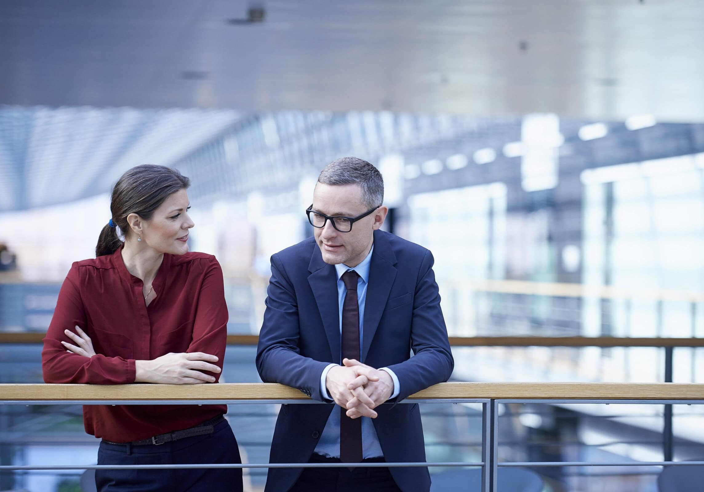 Businessman and businesswoman standing on a modern office balcony in discussion, symbolizing corporate 168极速一分钟赛车官方开奖历史记录赛果直播预测 coaching.