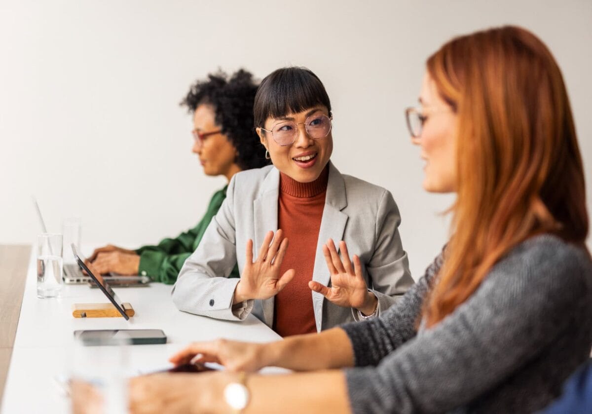 Three diverse women engaged in a business meeting at a conference table.