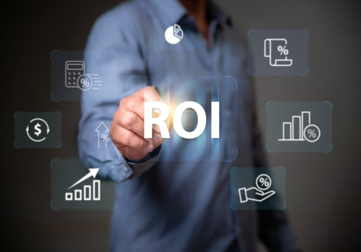 A person touching a holographic 'ROI' (Return on Investment) button surrounded by financial and calculation icons.