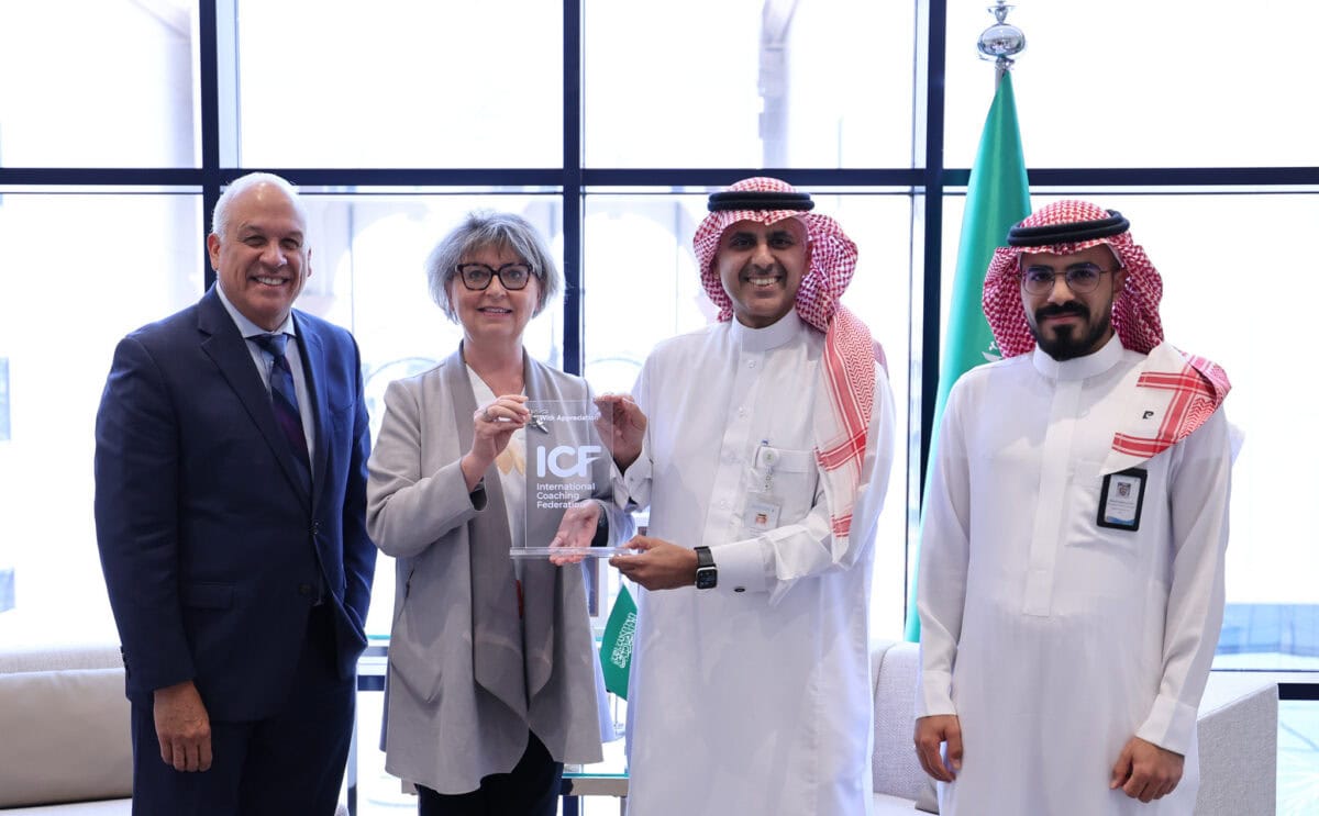 ICF CEO and a senior leader from the Saudi Food and Drug Authority smiling together while jointly holding a plaque, symbolizing a new partnership to promote coaching and professional development across the Middle East.
