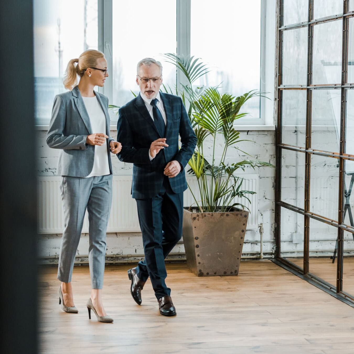 A man and a woman walk through an office always talking.