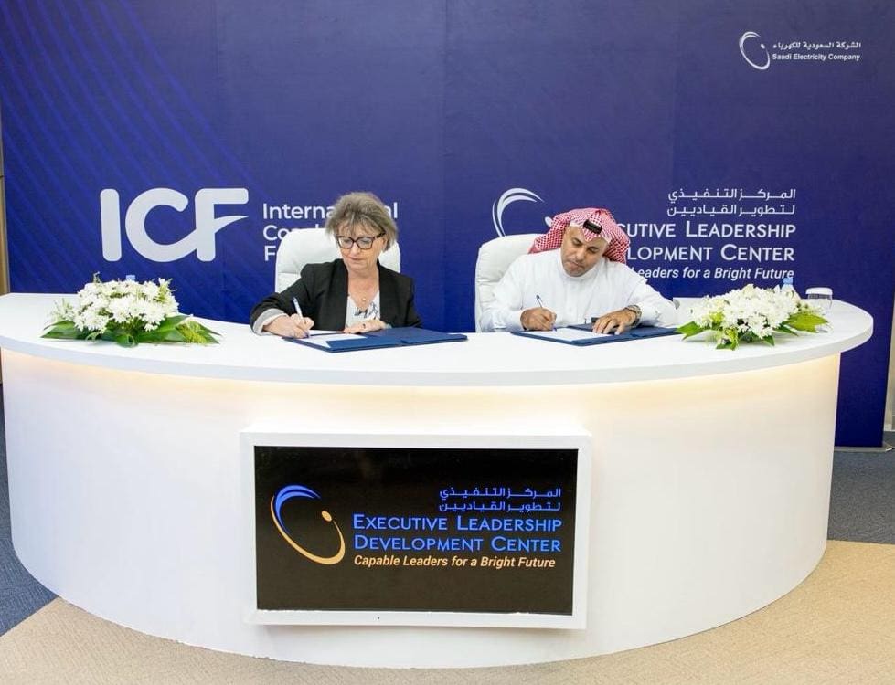 ICF CEO and a Saudi Electricity Company leader seated at a table, signing official documents to mark SEC’s organizational Membership with ICF — signifying a commitment to embedding coaching into leadership systems.