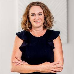 Elissa Kelly PCC MBA headshot photo, brown haired caucasian female in a black top with arms folded over her torso