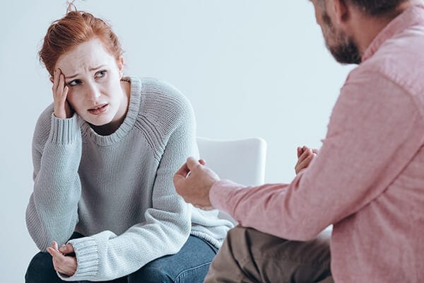 distraught woman listening to man in a counseling or coaching session