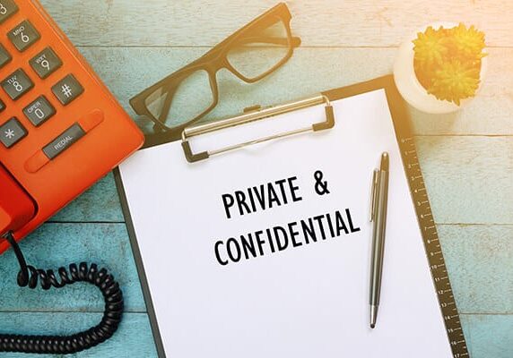 private & confidential written on a paper on a clipboard next to a pair of glasses a phone and a small succulent on a table