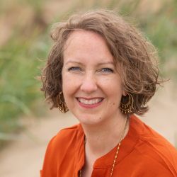 Jayne Morris MCC headshot photo, smiling woman outside wearing orange top