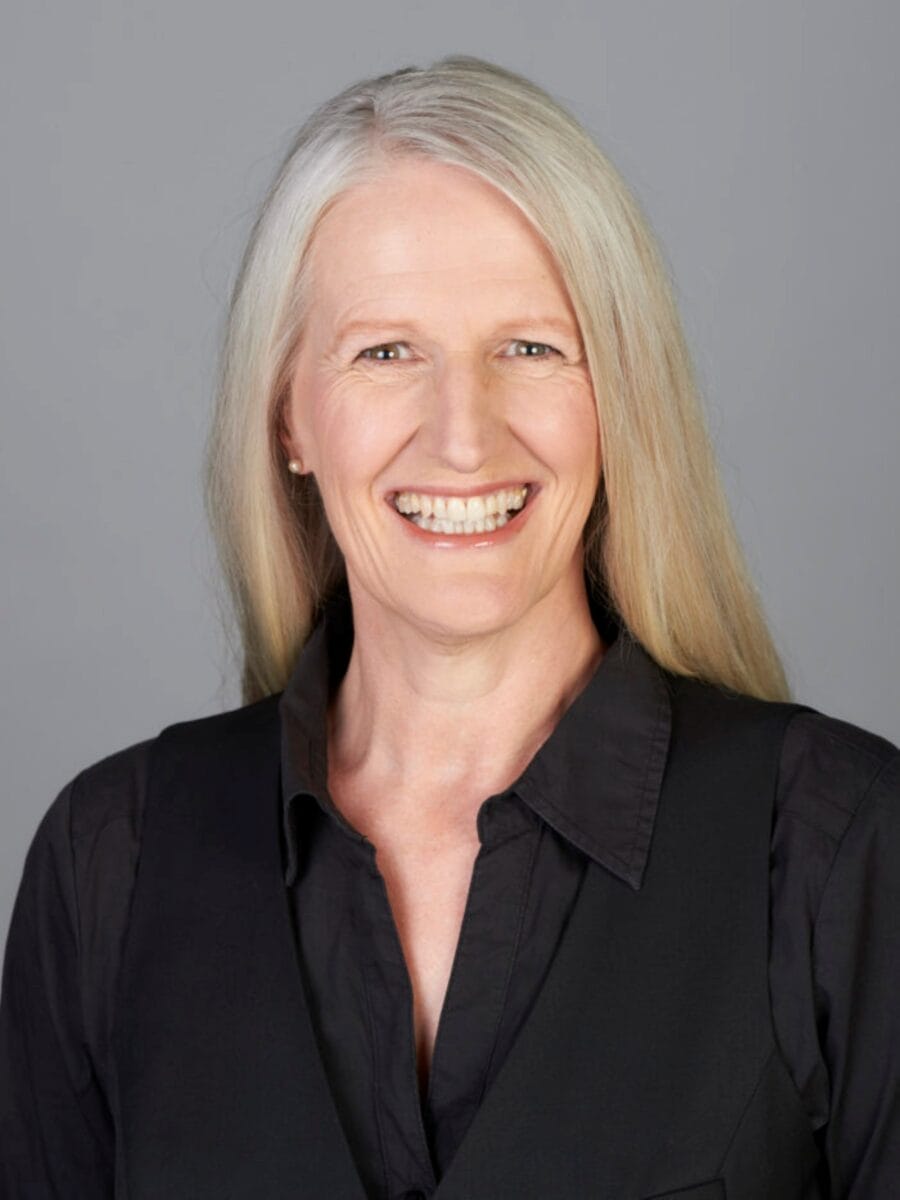 Kristen Dierolf ACTC MCC headshot photo, smiling woman with blond hair wearing black shirt in front of light gray background