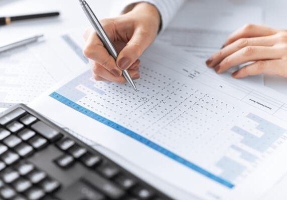 woman analyzing data on a piece of paper in front of a keyboard