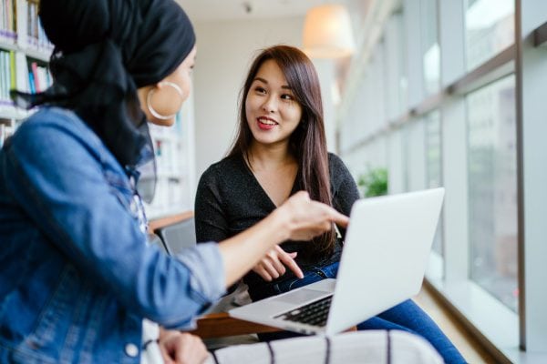two people meeting and smiling in front of a laptop one client one coach