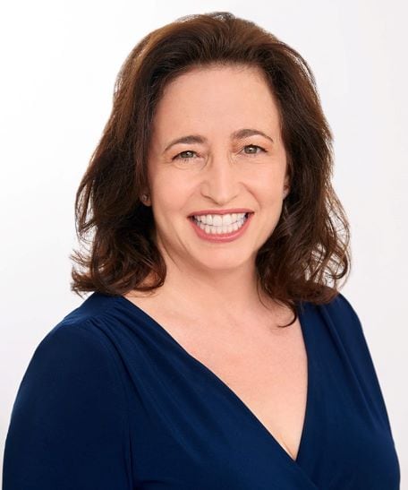 Rachel Karu PCC headshot photo, smiling woman with brown hair wearing a dark blue top in front of white background