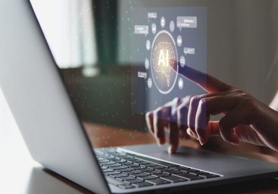 person working at a laptop and touching a projected screen with an AI icon on it