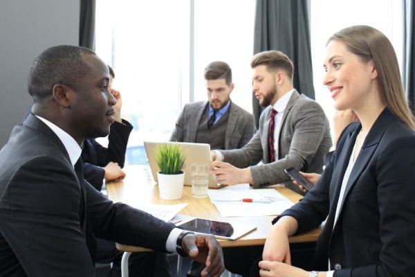 two people meeting with three others meeting behind at the same table