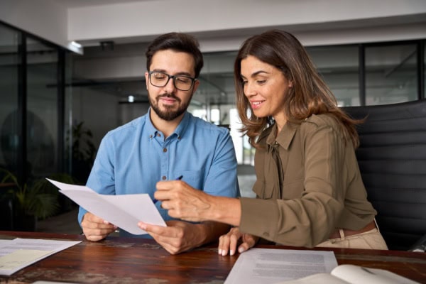 client holding papers while coach points things out on the papers with a pen