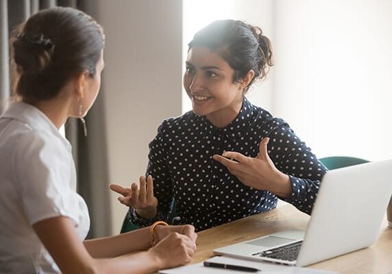 a coach and client engaging in a session at a table with a laptop