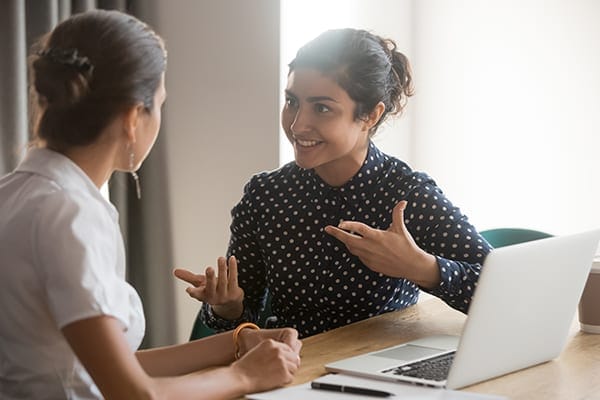 a coach and client engaging in a session at a table with a laptop