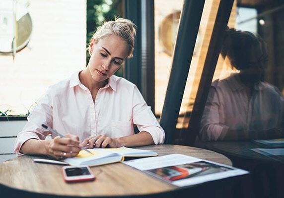 coach studying her notebook at a small round table