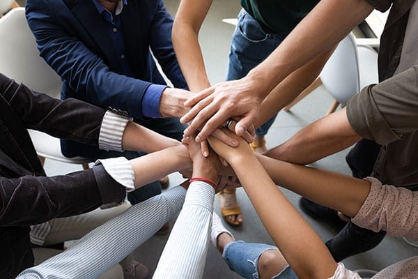 many people with hands in a circle working together