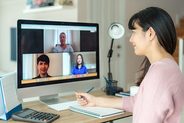 woman taking notes during an online coaching training session