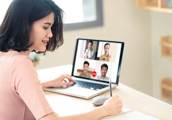 female coach networking via video call with four other professionals and taking notes