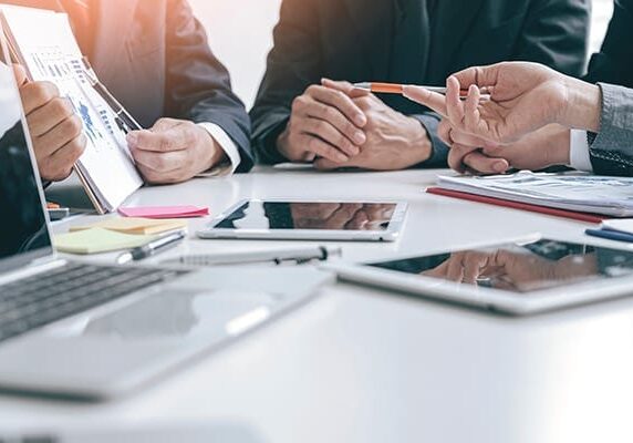 people's hands and devices at a conference table while in conversation
