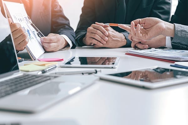 people's hands and devices at a conference table while in conversation