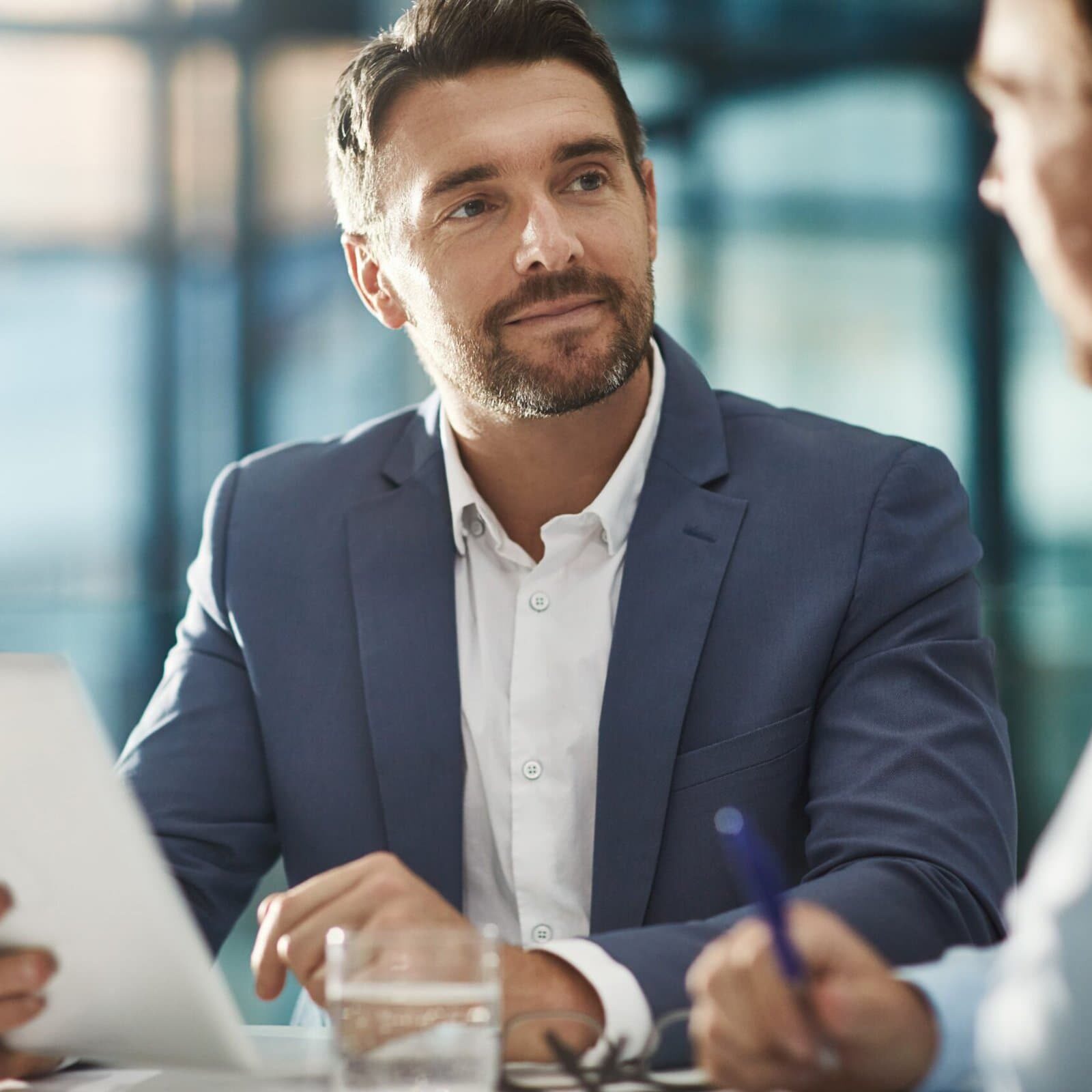 man holding a tablet looking at another who is speaking