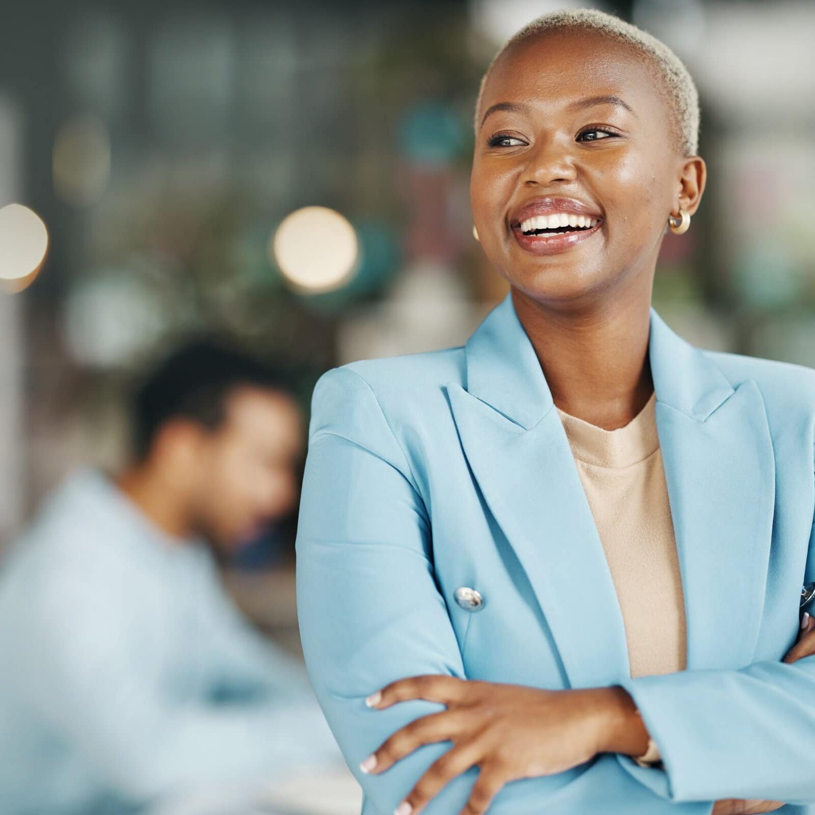 smiling woman with arms crossed and blurred office behind her