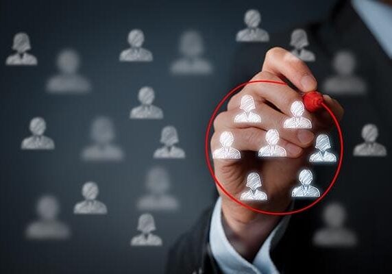 person circling a group of people icons in red on a transparent screen