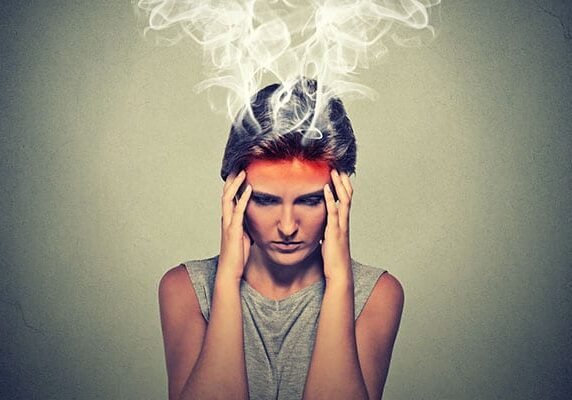 woman stressed with hands at temples and head emitting smoke