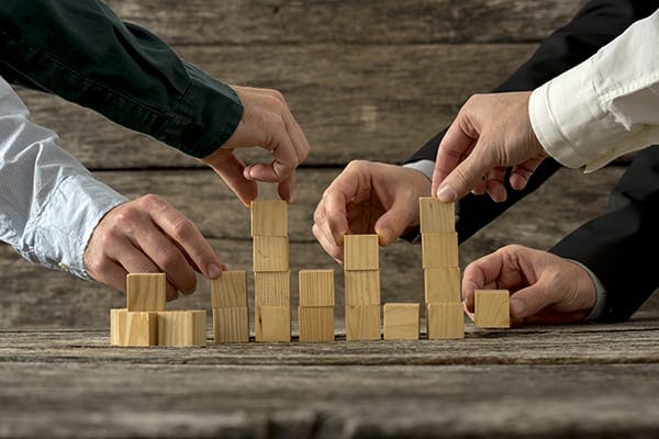 five people stacking cubed blocks of wood in different stacks