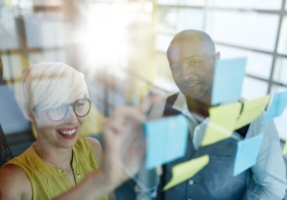 woman and man looking at sticky notes on a window