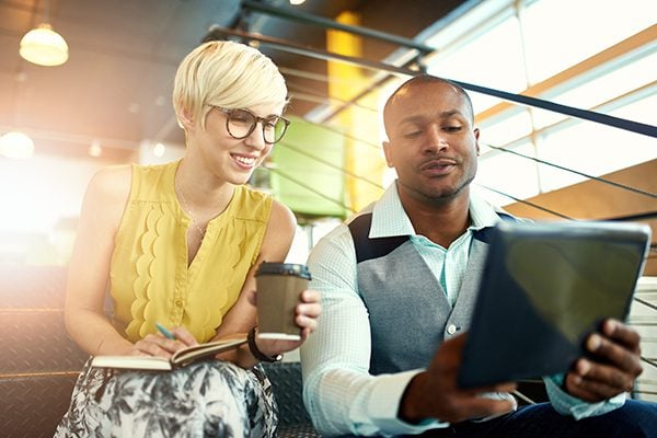 coach selling his coaching services to a woman who is holding a notebook and a coffee cup