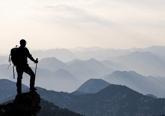 hiking man looking out at many hills or mountains