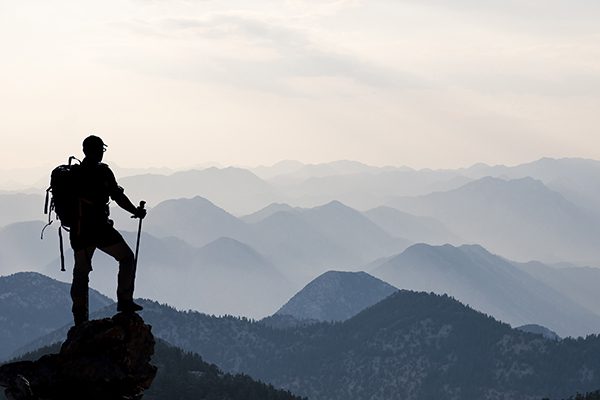 hiking man looking out at many hills or mountains