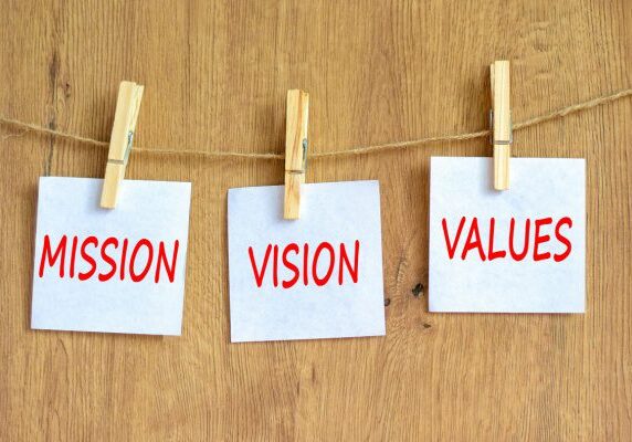 sticky notes on a string with clothes pins stating Mission Vision and Values
